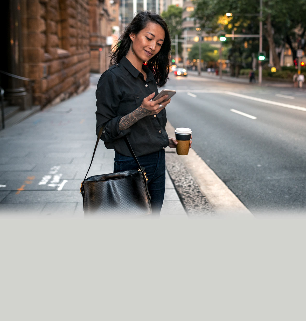 Woman standing on the kerb in a city about to cross the road, getting a phone notification