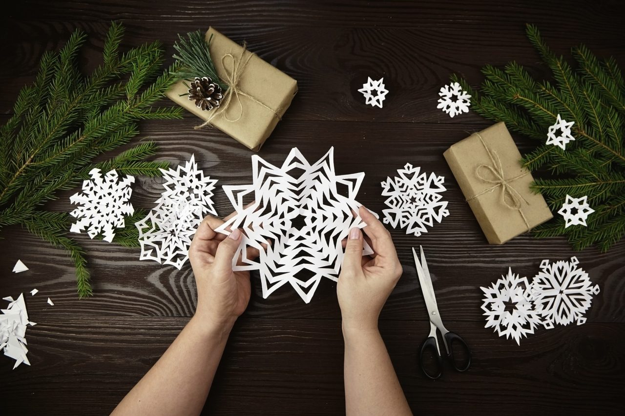 Paper snowflake decorations laid out on a table with gifts