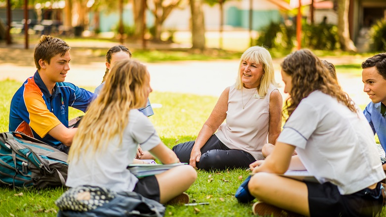 Teacher and students sit on the grass