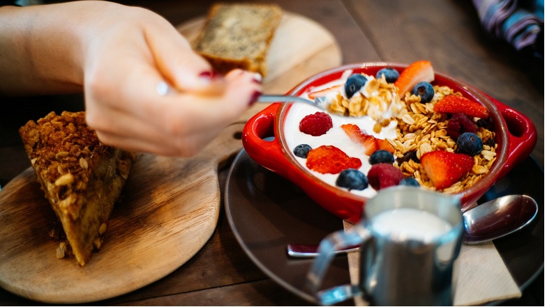 Lady spooning yogurt muesli and fruit 