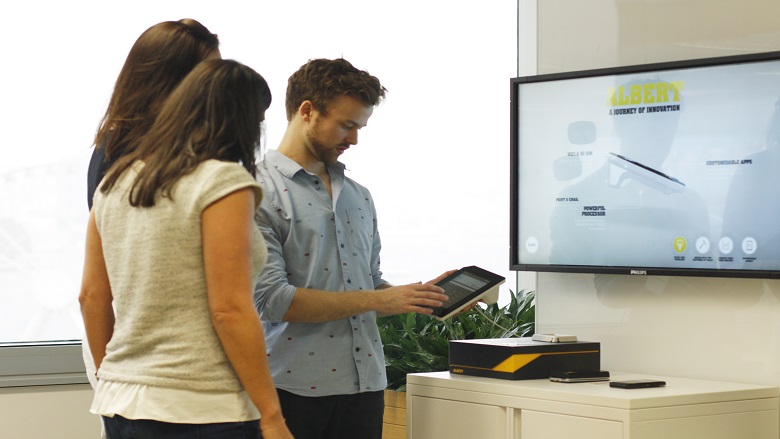 Three people stand around a computer screen