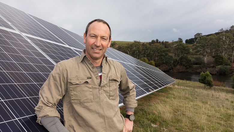 Farmer in front of solar panels