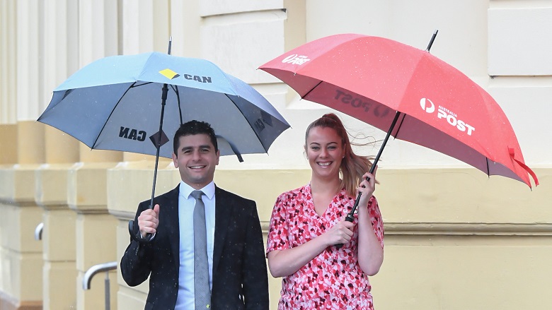 Australia Post and CBA employees with umbrellas