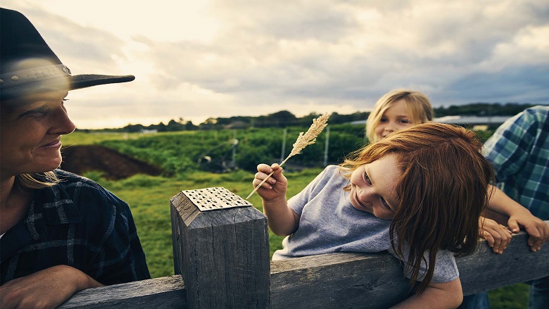 Mother and kids leaning on a fence on a farm