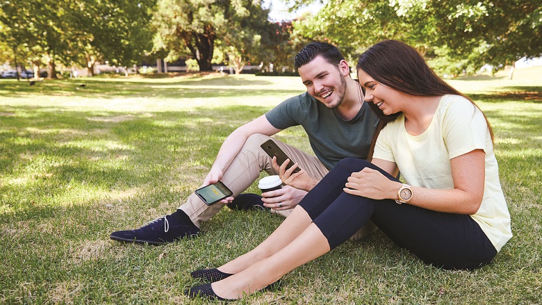 couple sitting on the grass with phone