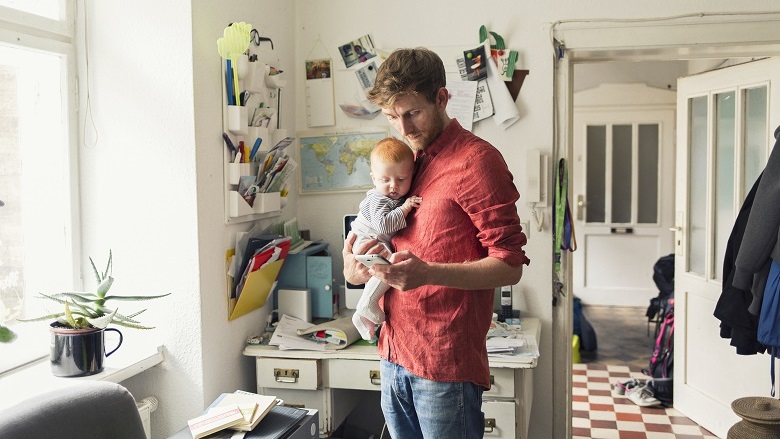 Man holding a baby looking at his phone