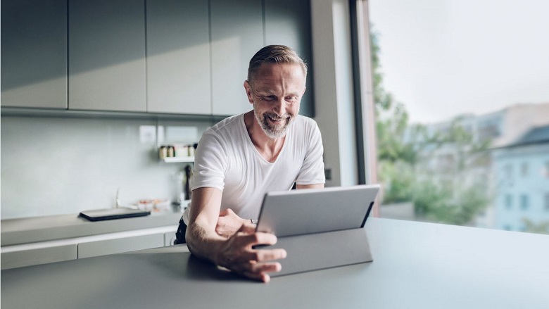 Man in kitchen looking at laptop screen