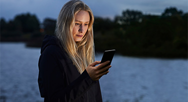 Woman looking at phone by a river