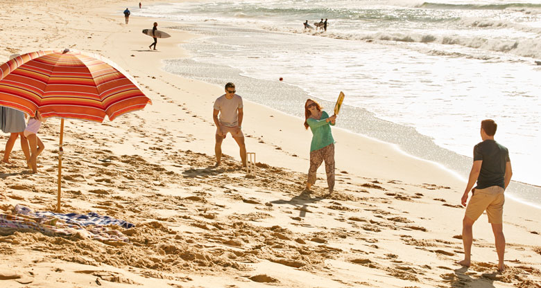 Family playing beach cricket