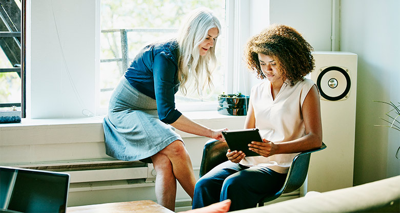 Businesswomen discussing project on digital tablet