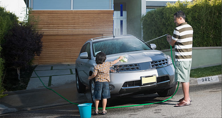 A father and his son washing their car in front of their house