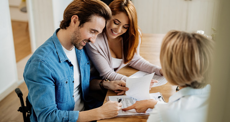 Couple signing a contract with agent looking on