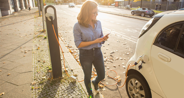 Young woman recharging her electric car