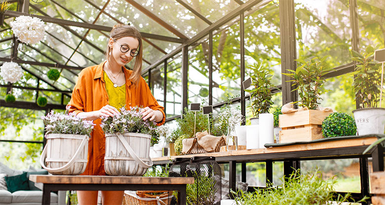 Woman tending to flowers in conservatory