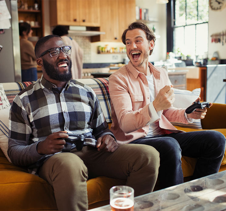 Two guys on couch playing game on game console