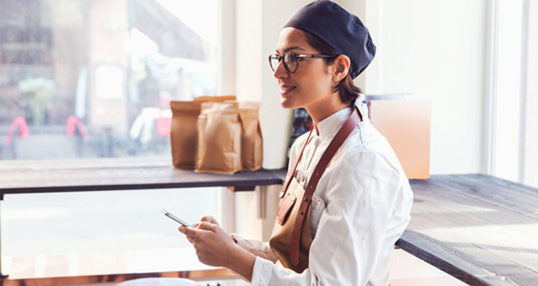 Image of a business owner in a chefs uniform on her phone