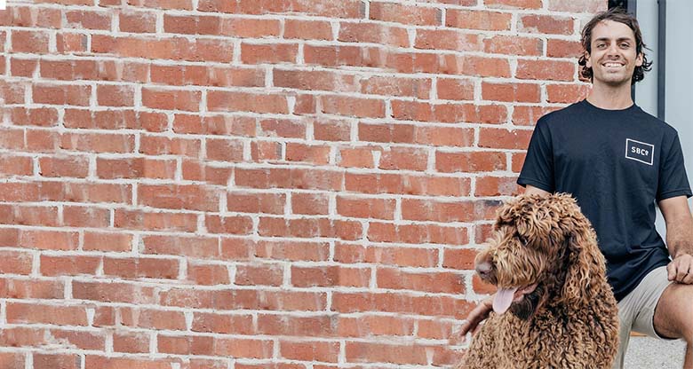 Man and dog standing next to brickwall