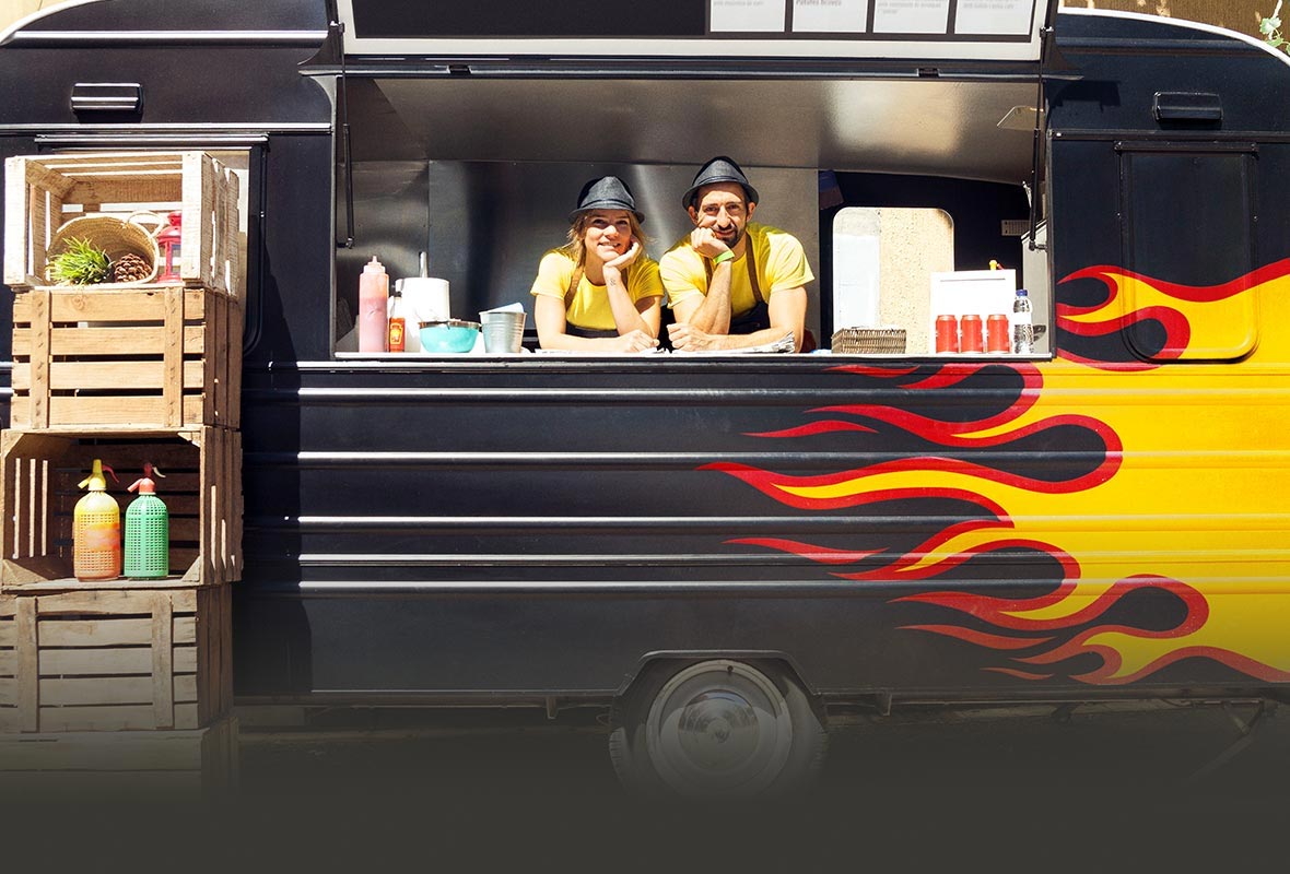 A couple working in a food truck with a flame painted on the side