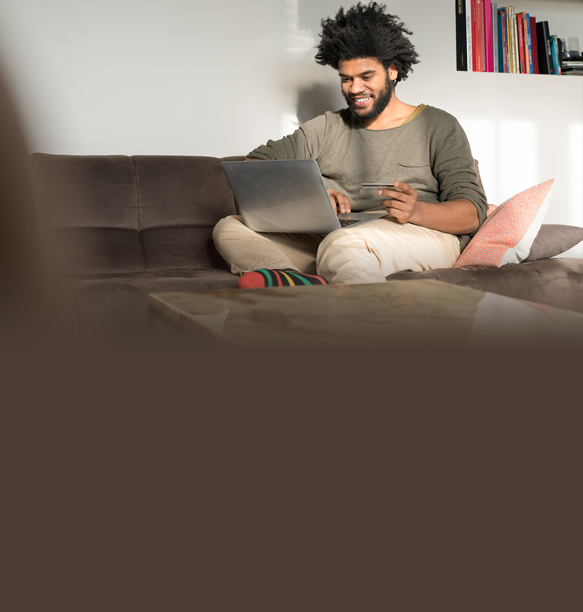 Person holding a credit card while looking at their laptop. 