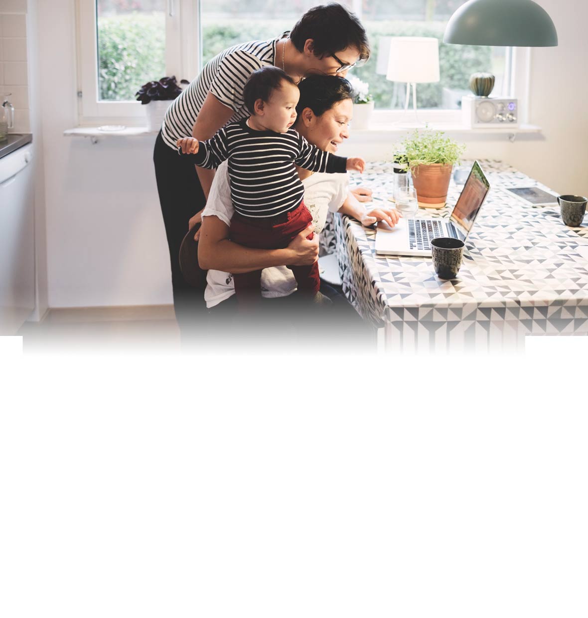 Family in kitchen looking at laptop