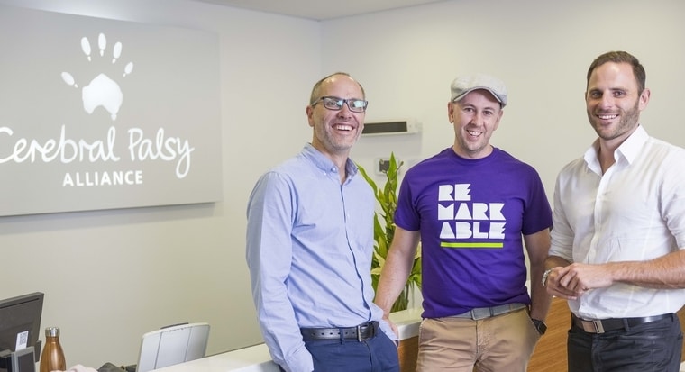 Three staff members smile in front of a CPA sign