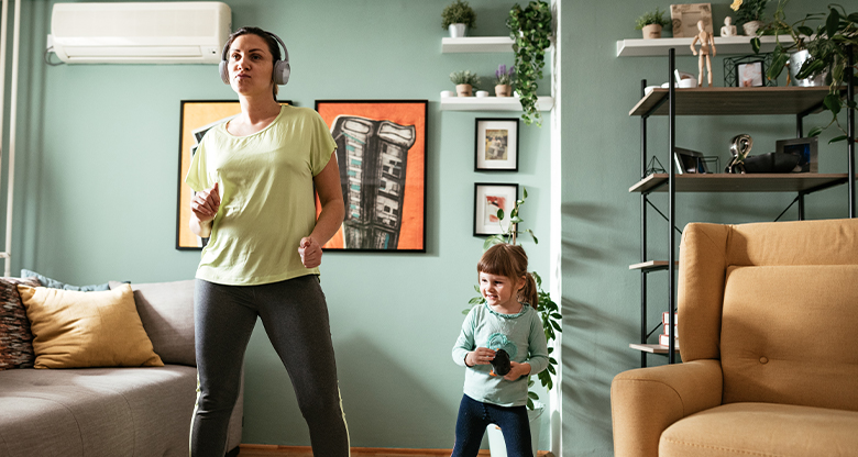 Mother and young daughter dancing in living room