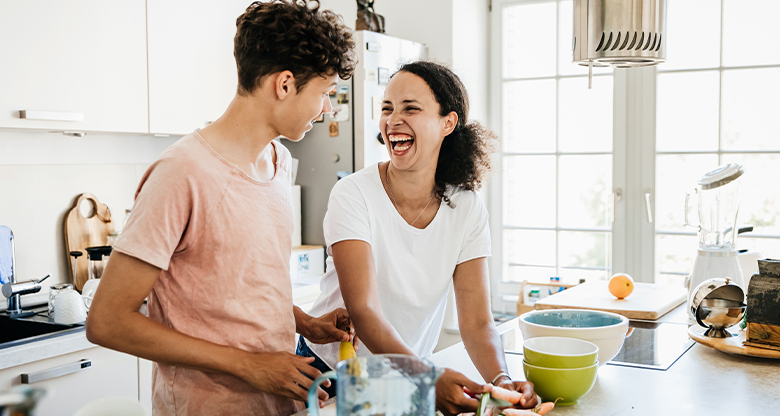 Young adults cooking in kitchen and smiling