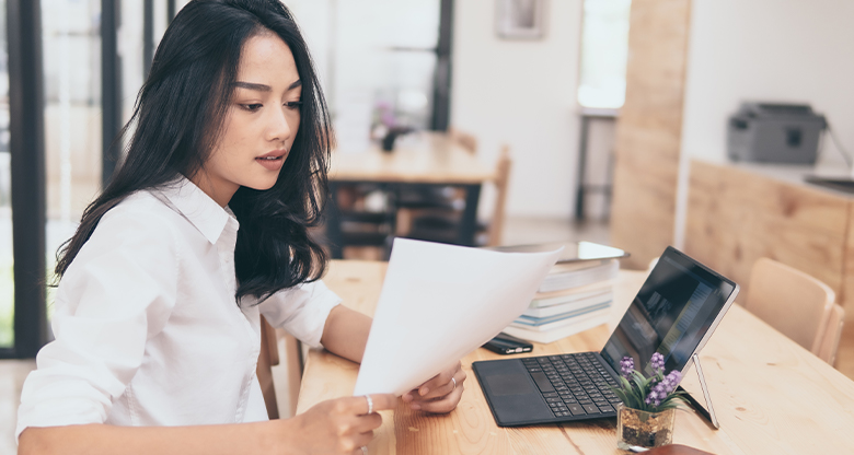 Young professional woman at desk with paper and laptop