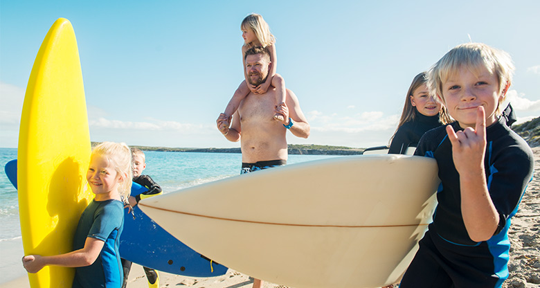 family on beach with surfboards