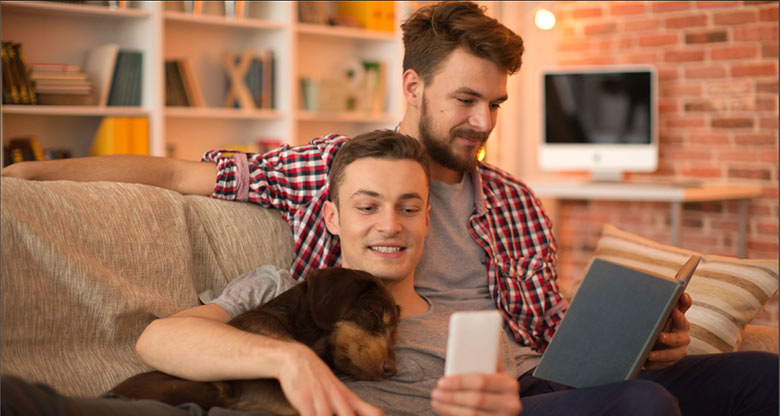 Young couple on couch with dog and laptop