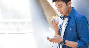 Guy eating and looking at  mobile phone