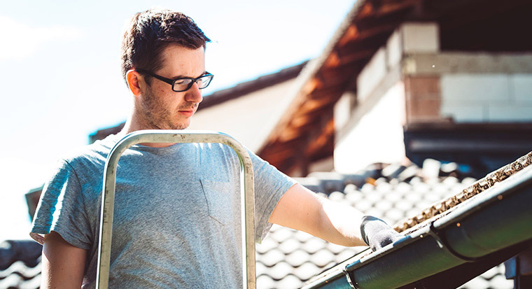 Man clearing gutters for home maintenance