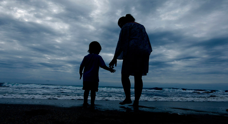 woman helping child at beach