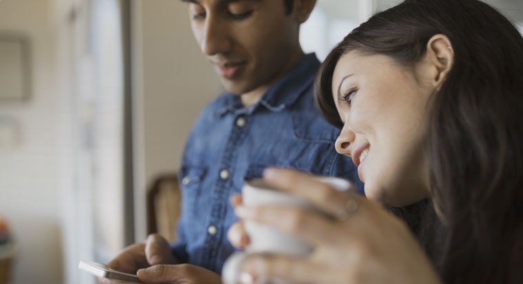 couple with coffee and device