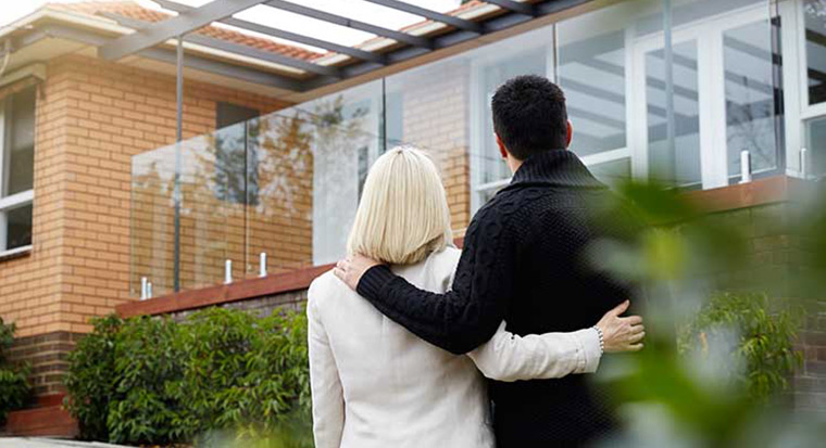 Couple arm in arm looking at house