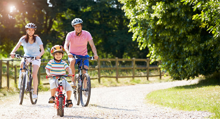 Two parents and a child riding their bikes in a park