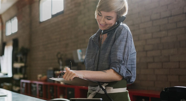 Woman business owner with clipboard and phone