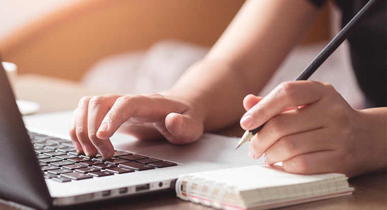 Hands typing on a laptop