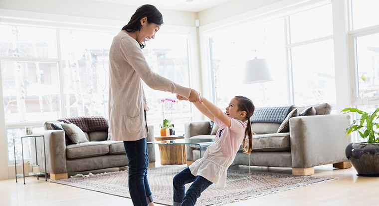mother and daughter dancing in living room