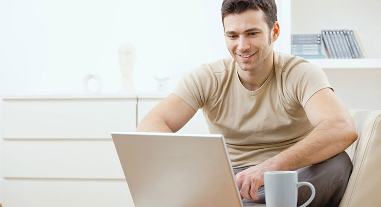 Man smiling at laptop thinking about borrowing money