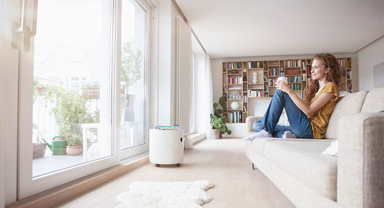 woman smiling on couch with bookcase