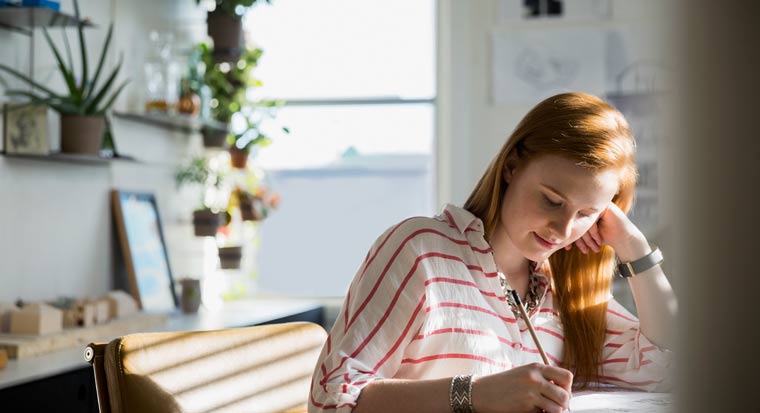 Girl writing at home office desk