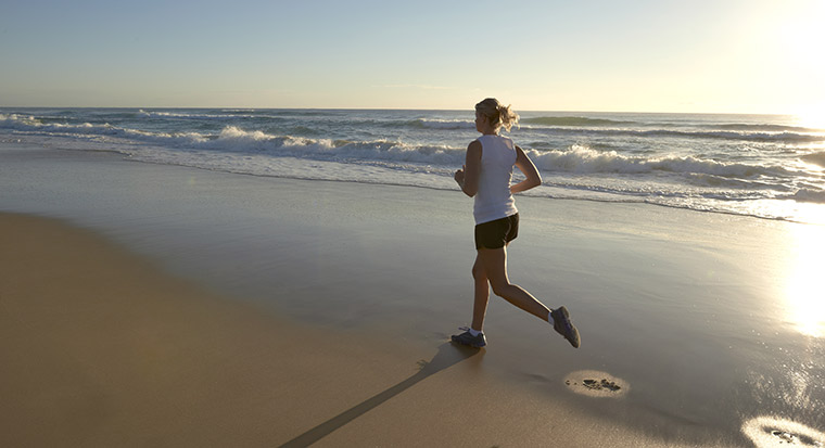 woman running on beach at sunrise