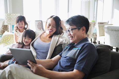 Family sitting on the sofa looking at a tablet