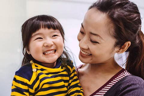 Chinese mother holding her daughter and smiling